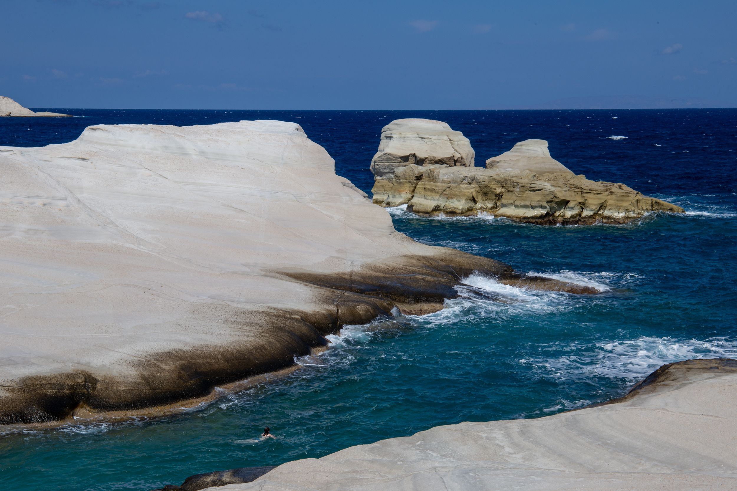 White volcanic rock formations at Sarakiniko Beach on Milos, Greece, with turquoise Aegean water.