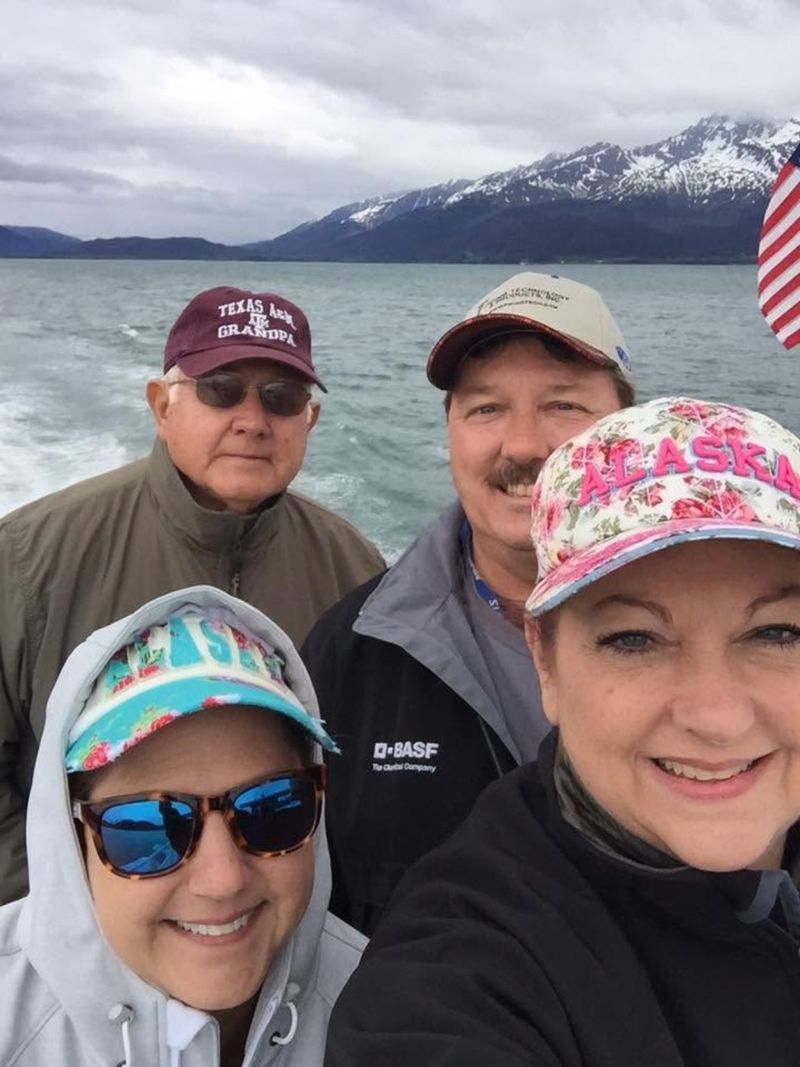 Traveler wearing a billed baseball cap under a rain jacket hood during a rainy Alaska cruise port day.