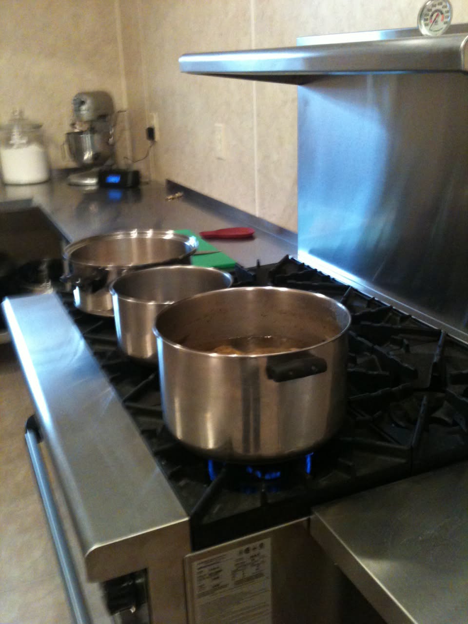 1st image Gina Renee cooking beside large stockpots in the commercial kitchen where she built her catering business over more than 14 years.