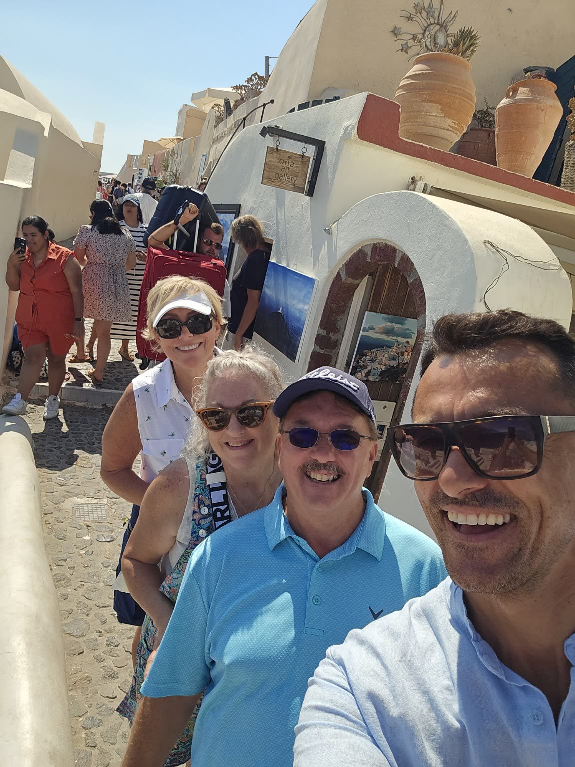 Gina Renee and traveling companions on a sunlit whitewashed lane in Oia, Santorini